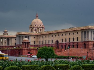 Rashtrapati Bhavan government building under a cloudy sky with green lawns